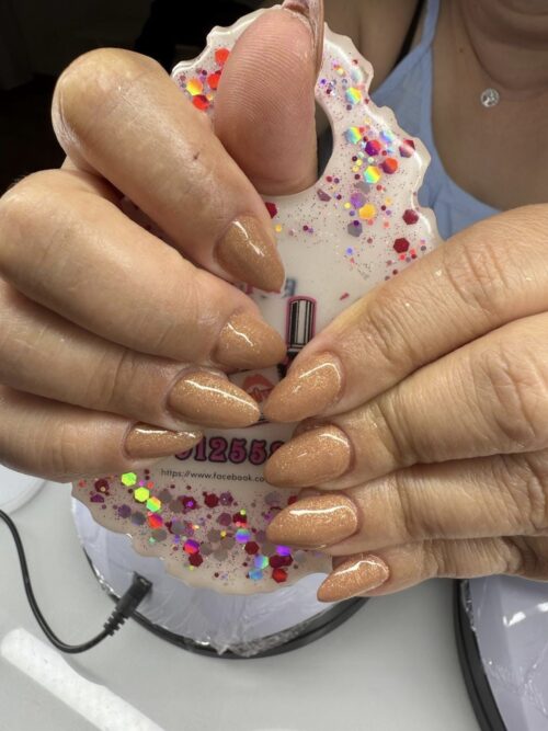 Mãos com unhas de acrílico aplicadas na Patrícia Nails, em Coruche, em tom claro com detalhes decorativos.