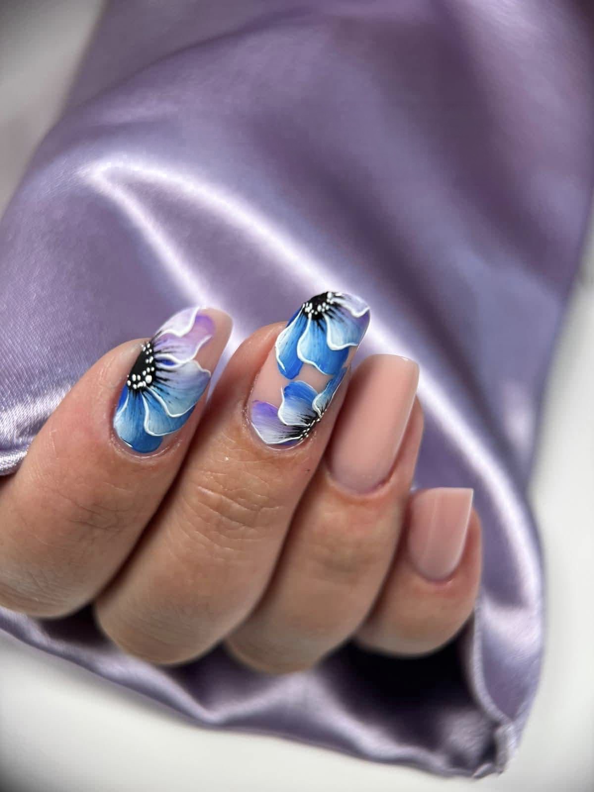Unhas de gel com extensão em tom nude e nail art de flores azuis pintadas à mão, feitas na Patrícia Nails em Coruche.